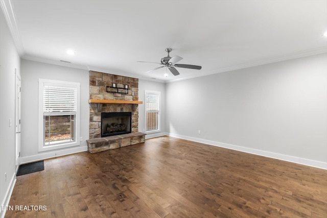 unfurnished living room with crown molding, plenty of natural light, a stone fireplace, and hardwood / wood-style floors