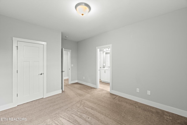 unfurnished bedroom featuring a closet, light colored carpet, and ensuite bathroom