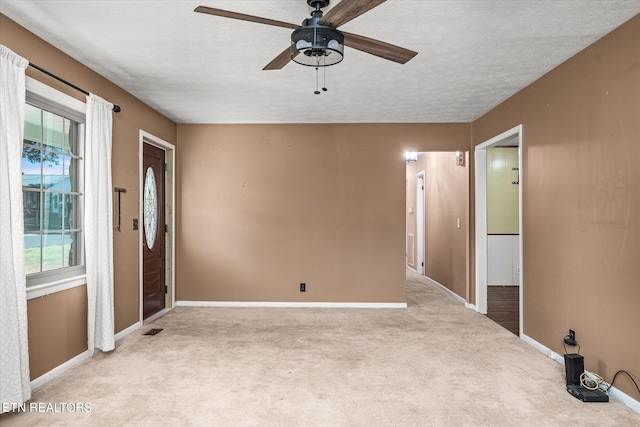 carpeted empty room with ceiling fan and a textured ceiling