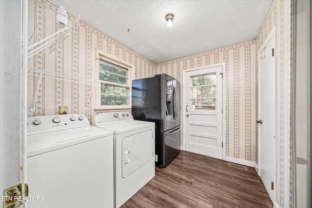 laundry room with dark wood-type flooring, a textured ceiling, washing machine and dryer, and a wealth of natural light