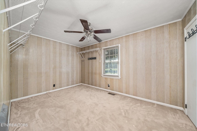 carpeted empty room with ornamental molding, a textured ceiling, and ceiling fan