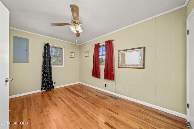 unfurnished room featuring a healthy amount of sunlight, hardwood / wood-style flooring, electric panel, and ceiling fan