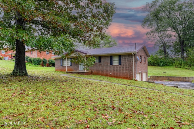 property exterior at dusk with a yard and a garage