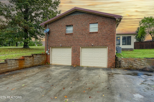 property exterior at dusk featuring central AC, a yard, and a garage