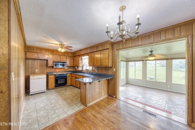 kitchen with black electric range oven, kitchen peninsula, a textured ceiling, pendant lighting, and light hardwood / wood-style floors