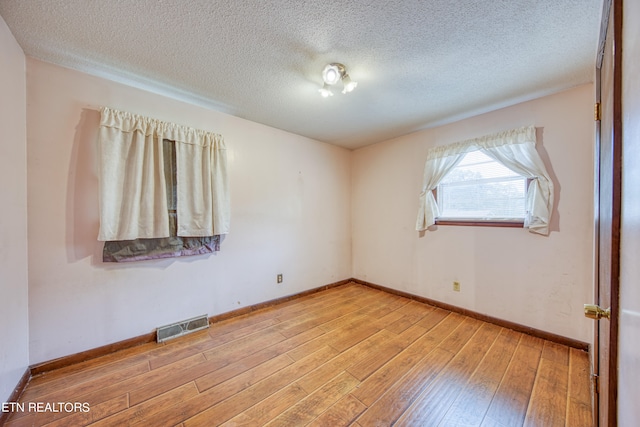 unfurnished room with light hardwood / wood-style floors and a textured ceiling