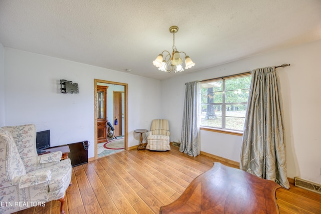 sitting room with a textured ceiling, a chandelier, and wood-type flooring