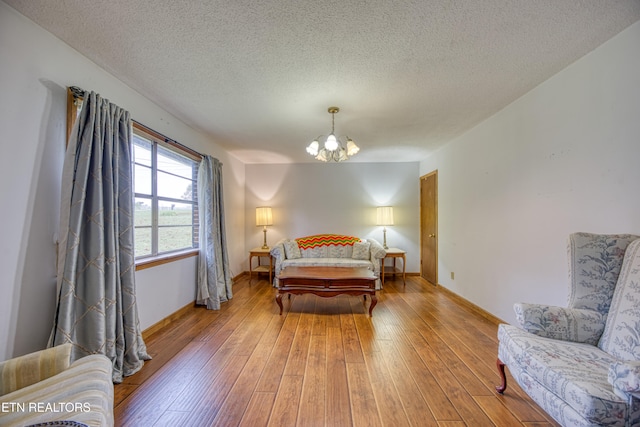 bedroom with an inviting chandelier, hardwood / wood-style floors, and a textured ceiling