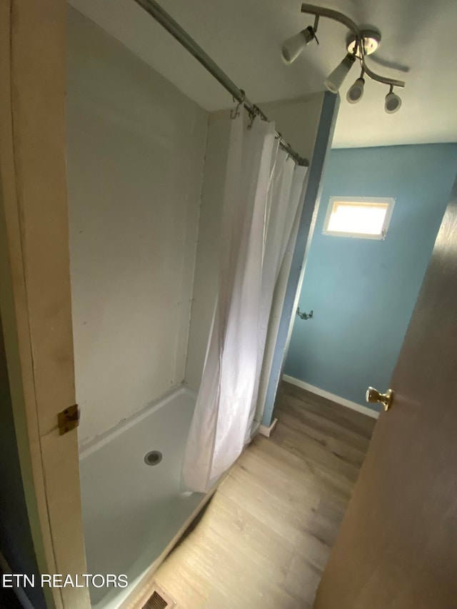 bathroom featuring wood-type flooring and a shower with shower curtain