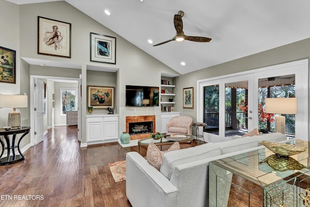 living room featuring ceiling fan, dark hardwood / wood-style flooring, built in shelves, vaulted ceiling, and french doors