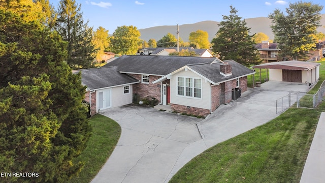 view of front facade with a mountain view, an outdoor structure, a garage, and a front lawn