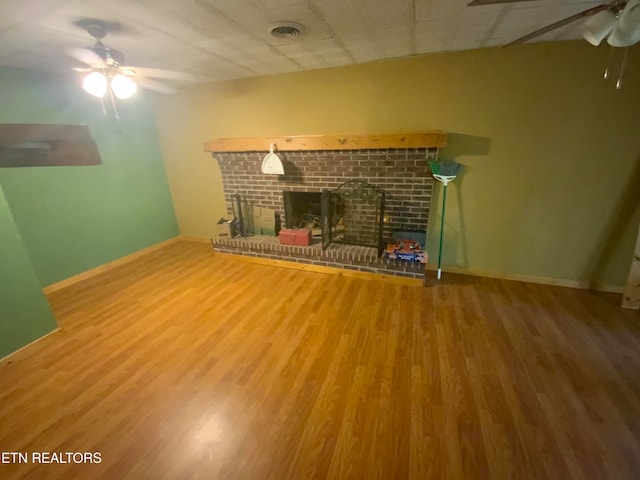 unfurnished living room featuring a brick fireplace, hardwood / wood-style floors, and ceiling fan