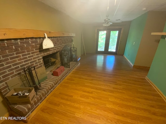 living room with a fireplace, french doors, light hardwood / wood-style floors, and ceiling fan