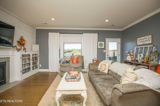 living room featuring crown molding, hardwood / wood-style flooring, a wealth of natural light, and a tile fireplace