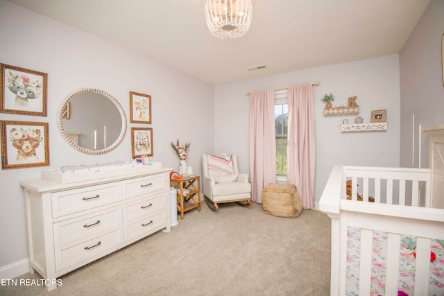 carpeted bedroom featuring a nursery area and a chandelier