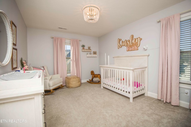 bedroom featuring a nursery area, a chandelier, and carpet flooring