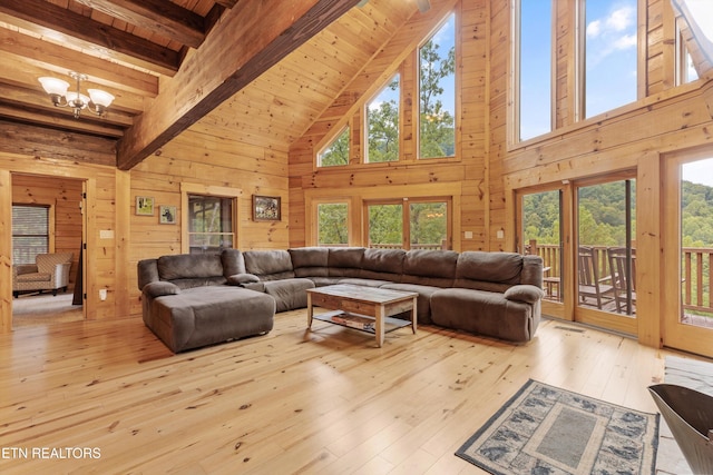 living room featuring high vaulted ceiling, a wealth of natural light, a chandelier, and light hardwood / wood-style floors