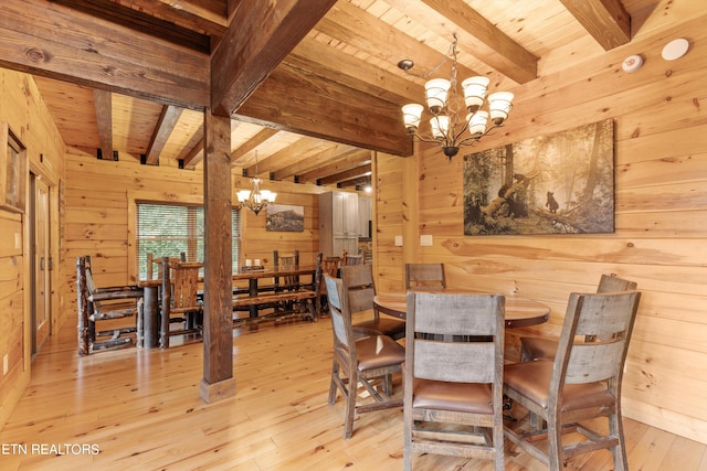 dining area with beamed ceiling, wooden walls, and light hardwood / wood-style flooring