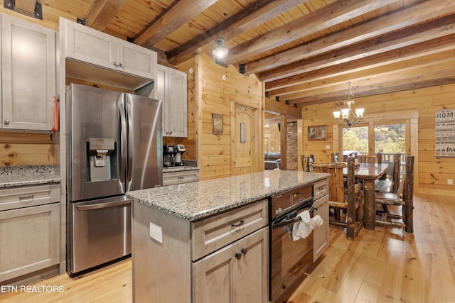 kitchen with wood walls, a kitchen island, light hardwood / wood-style flooring, stainless steel refrigerator with ice dispenser, and black oven