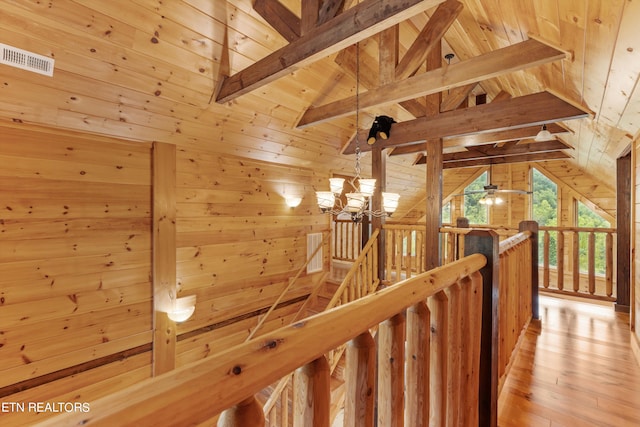 corridor featuring vaulted ceiling with beams, wood walls, wooden ceiling, a notable chandelier, and light wood-type flooring