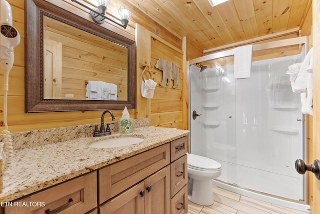 bathroom featuring vanity, wooden walls, a shower with shower door, wooden ceiling, and toilet