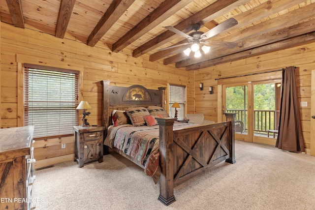 carpeted bedroom with access to exterior, multiple windows, and wood walls