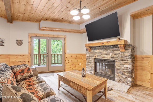 living room featuring wood walls, french doors, light hardwood / wood-style flooring, wooden ceiling, and a fireplace