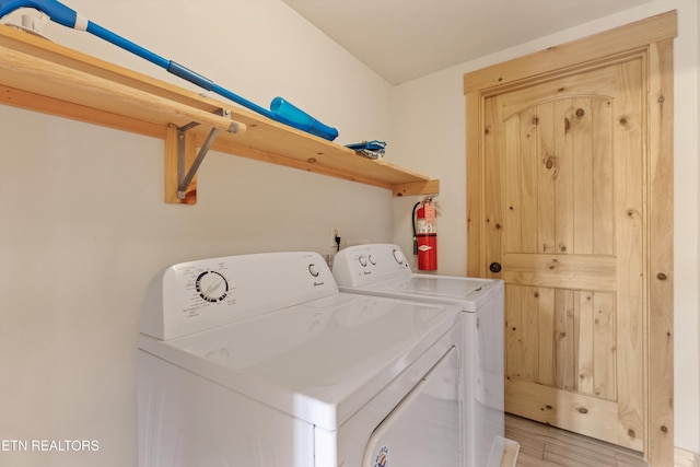 laundry room with washing machine and dryer and light wood-type flooring