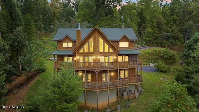 rear view of property featuring a balcony and a lawn