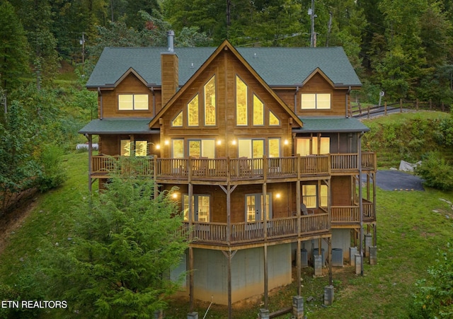 rear view of property featuring a deck, a lawn, and central air condition unit