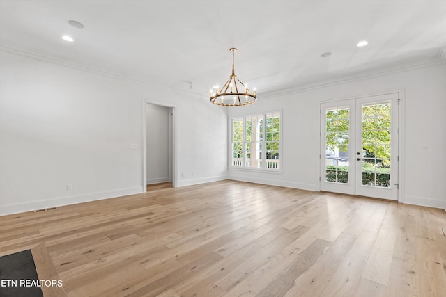 spare room with light hardwood / wood-style floors, french doors, crown molding, and a chandelier