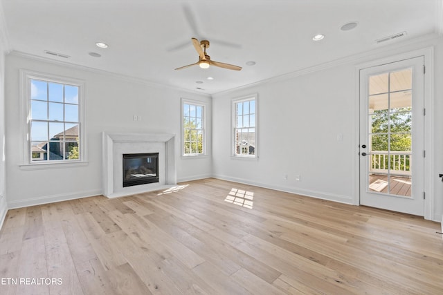 unfurnished living room featuring a high end fireplace, light hardwood / wood-style floors, ceiling fan, and crown molding