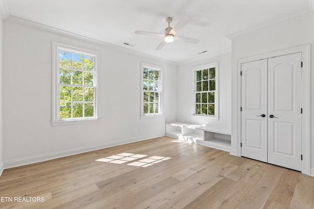 unfurnished bedroom featuring ceiling fan, light wood-type flooring, crown molding, and a closet