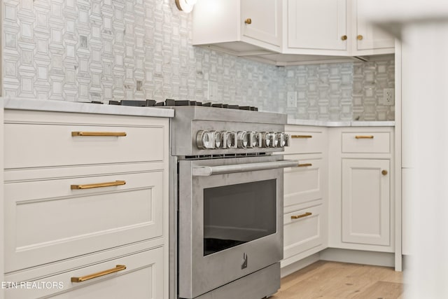 kitchen with white cabinets, decorative backsplash, light wood-type flooring, and stainless steel electric range oven