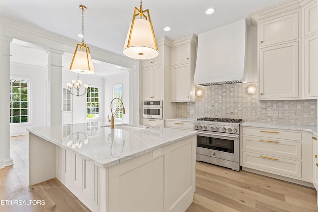 kitchen with sink, custom range hood, stainless steel appliances, and an island with sink