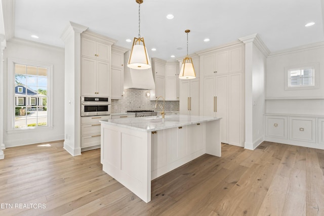 kitchen featuring light stone counters, pendant lighting, stainless steel appliances, and light hardwood / wood-style floors