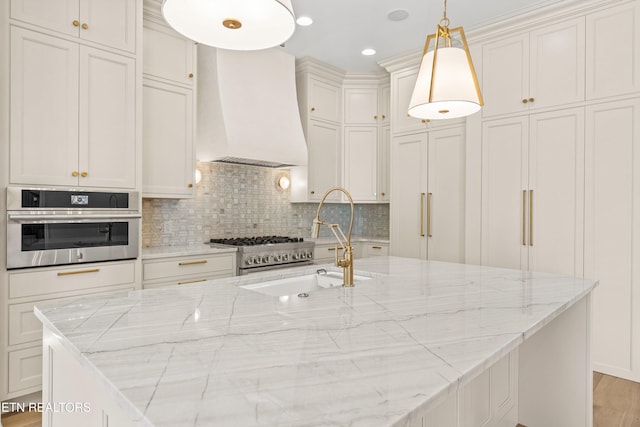 kitchen with pendant lighting, custom exhaust hood, sink, light stone countertops, and stainless steel appliances