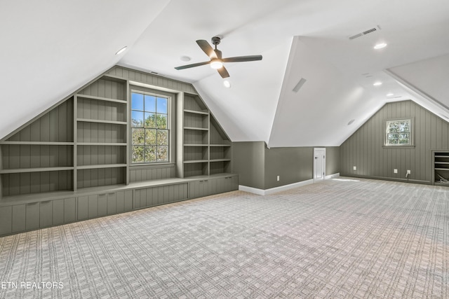 bonus room featuring ceiling fan, built in features, light colored carpet, and lofted ceiling