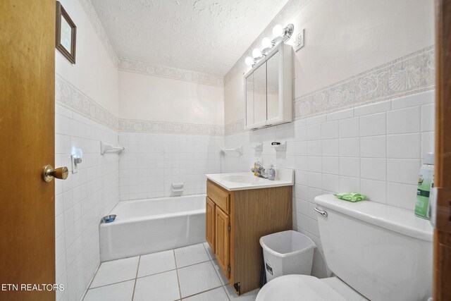 9832 Clift Rd, Strawberry Plains, TN 37871 - full bath with tile walls, toilet, a wainscoted wall, a textured ceiling, and tile patterned floors