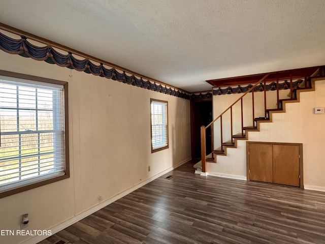 9832 Clift Rd, Strawberry Plains, TN 37871 - empty room featuring a textured ceiling, baseboards, dark wood finished floors, and stairs