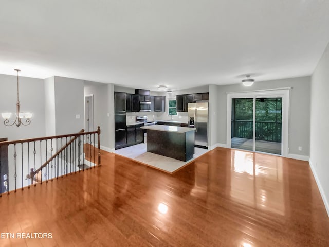 kitchen with stainless steel appliances, a kitchen island, a notable chandelier, and light wood-type flooring