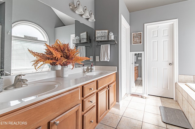 bathroom featuring a relaxing tiled tub, vanity, and tile patterned flooring