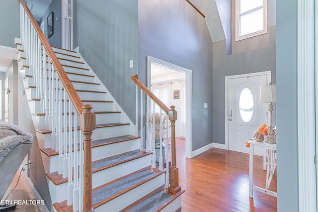 entryway featuring light wood-type flooring and a towering ceiling