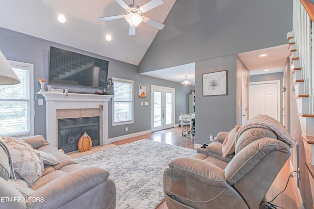 living room featuring french doors, ceiling fan, high vaulted ceiling, and a tile fireplace