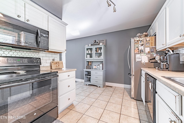 kitchen with tasteful backsplash, white cabinets, black appliances, and light tile patterned floors