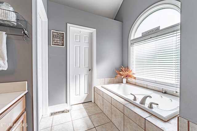 bathroom featuring a relaxing tiled tub, tile patterned flooring, and vanity