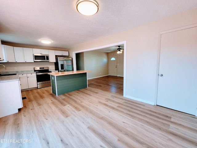 kitchen featuring a kitchen island, light hardwood / wood-style flooring, sink, stainless steel appliances, and white cabinetry