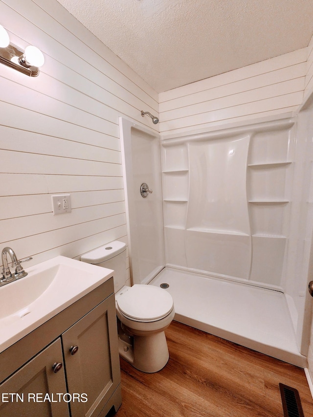 bathroom featuring vanity, walk in shower, wood-type flooring, and a textured ceiling