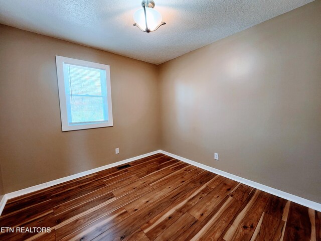 unfurnished room with hardwood / wood-style floors and a textured ceiling