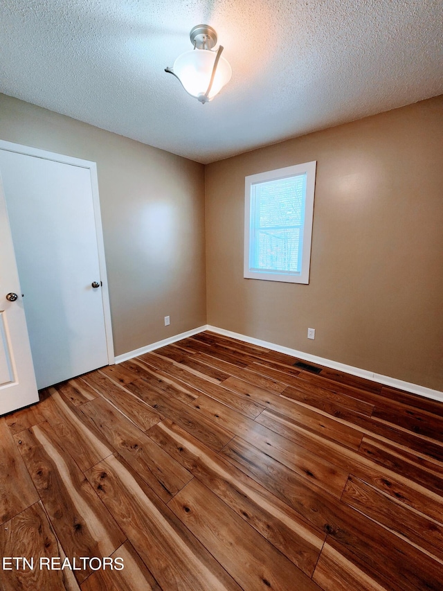 spare room with wood-type flooring and a textured ceiling